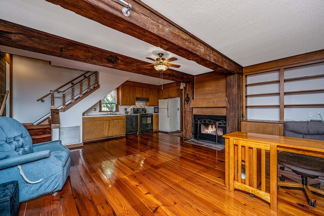 living room featuring ceiling fan, beamed ceiling, sink, a textured ceiling, and dark wood-type flooring