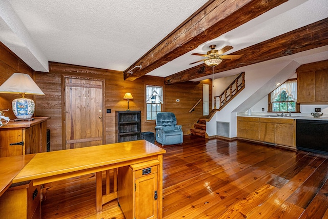 kitchen with dark hardwood / wood-style flooring, beamed ceiling, a textured ceiling, ceiling fan, and wooden walls