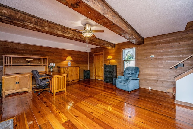 interior space with wood-type flooring, wood walls, ceiling fan, and a textured ceiling