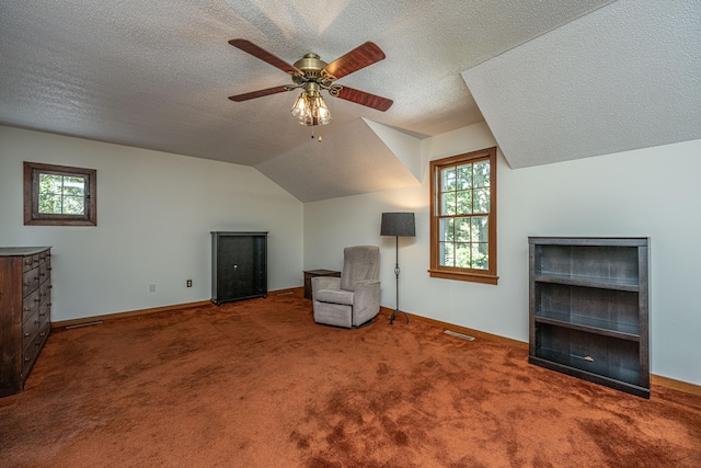 unfurnished room with ceiling fan, carpet floors, lofted ceiling, and a textured ceiling