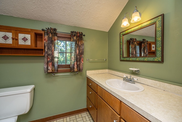 bathroom featuring tile patterned flooring, a textured ceiling, vaulted ceiling, vanity, and toilet