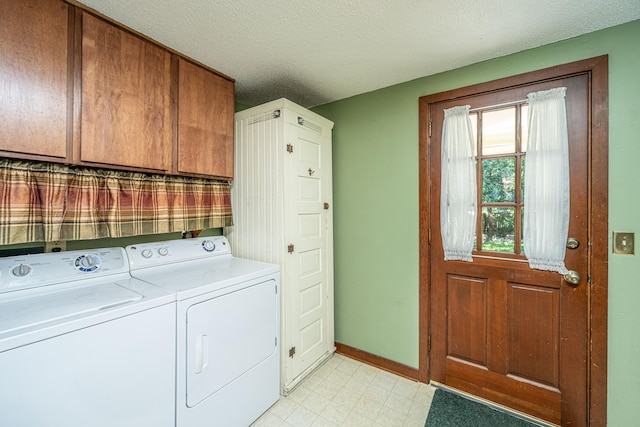 washroom with a textured ceiling, washing machine and dryer, and cabinets