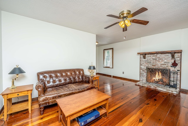 living room featuring wood-type flooring, a textured ceiling, a fireplace, and ceiling fan