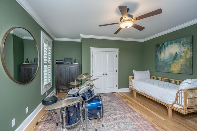 bedroom with wood finished floors, baseboards, and ornamental molding