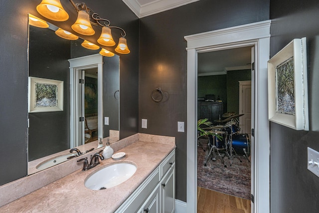 bathroom featuring vanity, wood finished floors, a chandelier, and ornamental molding