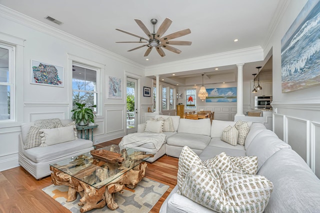 living room with decorative columns, visible vents, ceiling fan, and a decorative wall