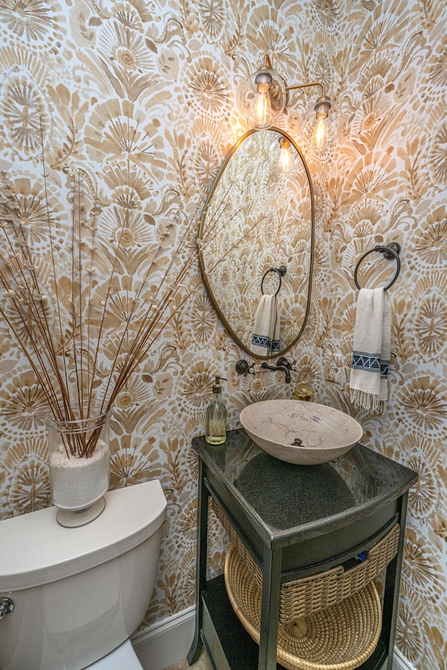 half bathroom featuring wallpapered walls, toilet, vanity, and baseboards