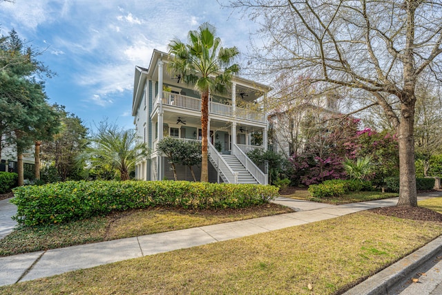 view of front of property with a front lawn, ceiling fan, a porch, stairs, and a balcony