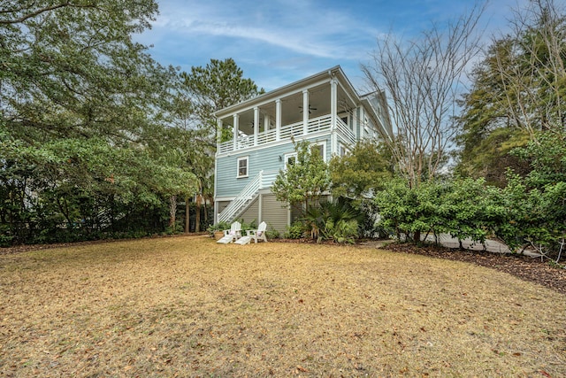 view of side of home with a balcony, a yard, and ceiling fan