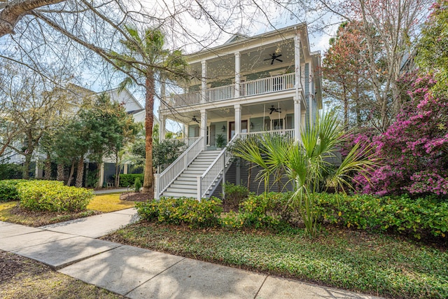 view of front of home with a balcony, stairway, covered porch, and ceiling fan