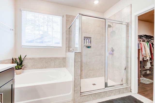 bathroom with vanity, wood-type flooring, and plus walk in shower