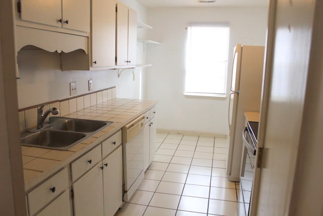 kitchen with dishwasher, tile countertops, plenty of natural light, and sink