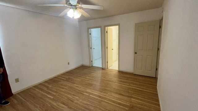 interior space with a walk in closet, ensuite bath, ceiling fan, light hardwood / wood-style flooring, and a closet