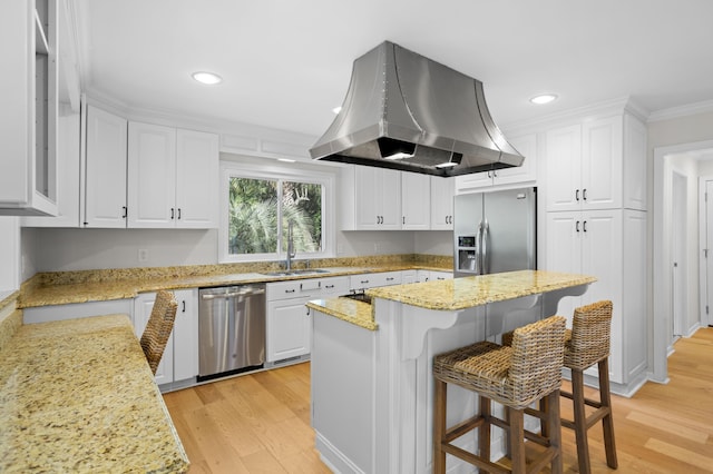 kitchen with crown molding, a kitchen breakfast bar, island range hood, white cabinets, and stainless steel appliances