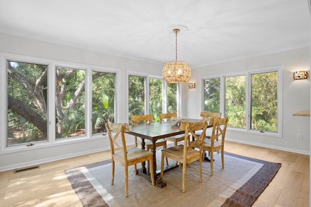 dining space with visible vents, light wood finished floors, baseboards, an inviting chandelier, and crown molding