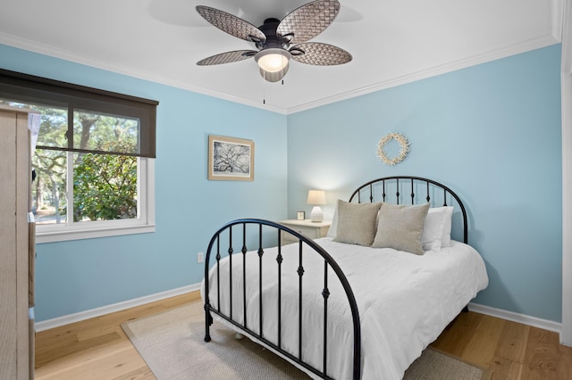 bedroom with wood finished floors, baseboards, and ornamental molding