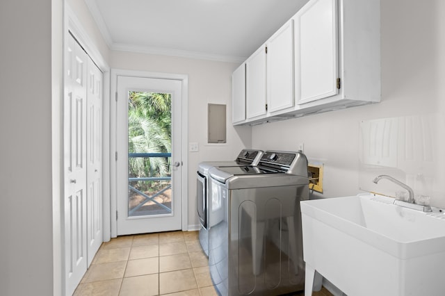 clothes washing area featuring washer and clothes dryer, a sink, cabinet space, crown molding, and light tile patterned floors