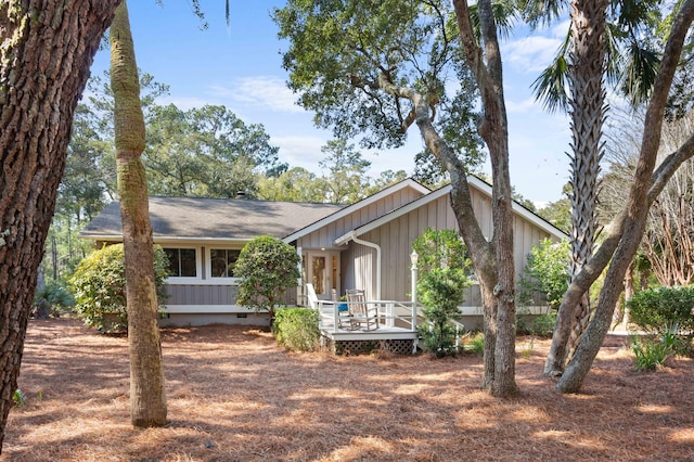 view of front of property with crawl space, board and batten siding, a wooden deck, and a shingled roof