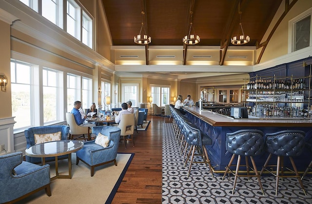 interior space featuring a chandelier, a community bar, wooden ceiling, wood finished floors, and high vaulted ceiling