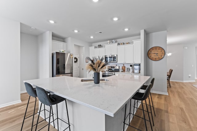 68 Red Bluff St, Summerville, SC 29483 - kitchen with a kitchen breakfast bar, white cabinets, stainless steel appliances, and light wood-style floors