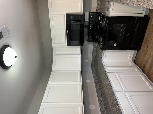 kitchen with black oven and white cabinets