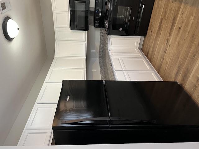 kitchen featuring wooden walls and white cabinets