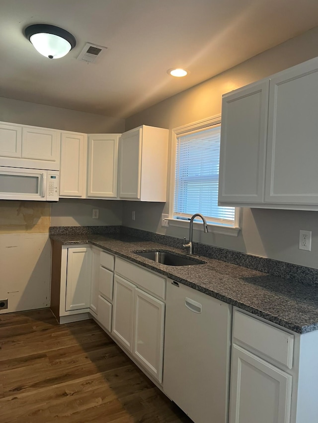 kitchen with sink, dark stone countertops, white cabinets, dark wood-type flooring, and white appliances