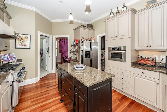 kitchen with crown molding, light wood-style floors, dark stone countertops, a center island, and stainless steel appliances