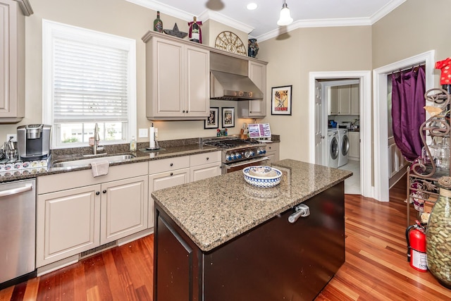 kitchen with wall chimney range hood, independent washer and dryer, appliances with stainless steel finishes, and ornamental molding