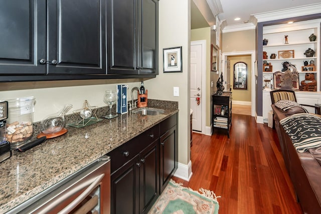 interior space with wet bar, crown molding, dark wood finished floors, a sink, and beverage cooler