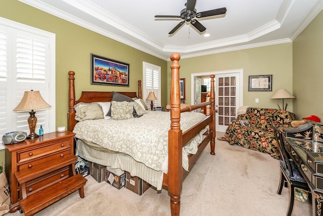 bedroom with carpet floors, a tray ceiling, ornamental molding, and ceiling fan