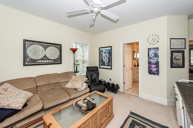 living room with light colored carpet, a ceiling fan, and baseboards