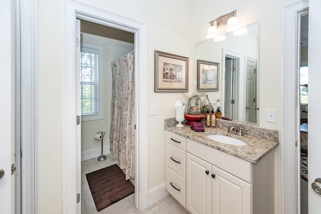 bathroom with vanity, baseboards, and tile patterned flooring