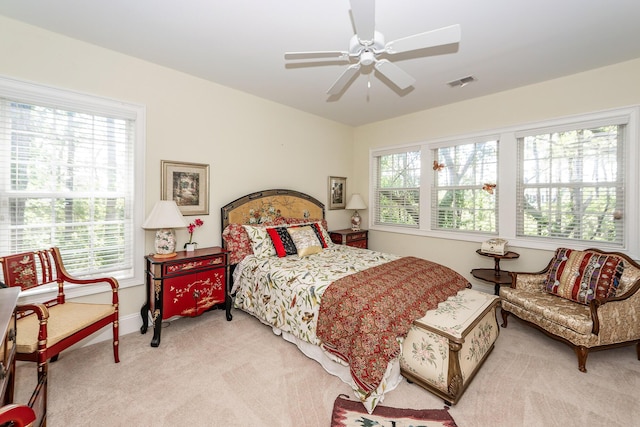 bedroom with light colored carpet, ceiling fan, visible vents, and baseboards