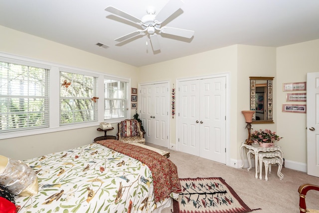 carpeted bedroom with multiple closets, baseboards, a ceiling fan, and visible vents