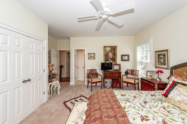 bedroom with ceiling fan, light carpet, and a closet