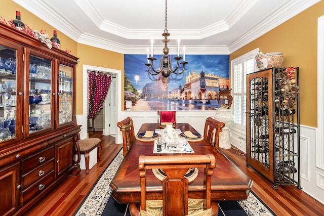 dining room featuring a raised ceiling, ornamental molding, wood finished floors, and a notable chandelier