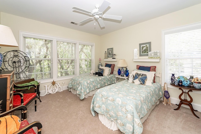 carpeted bedroom with visible vents, a ceiling fan, and baseboards