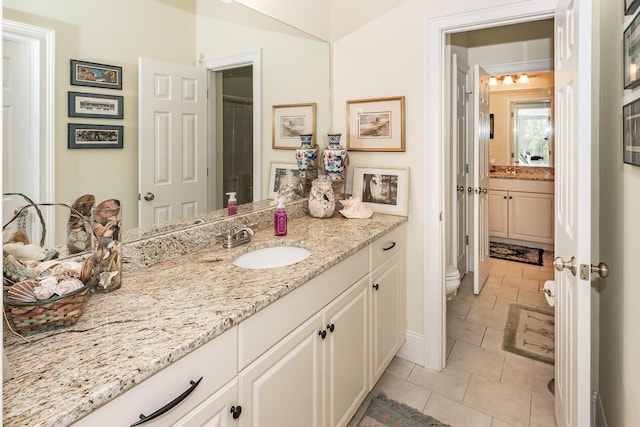 full bath with toilet, tile patterned floors, baseboards, and vanity