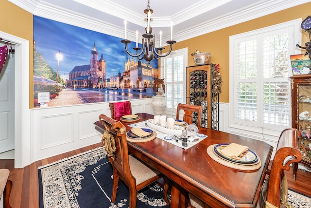 dining room with an inviting chandelier, a decorative wall, a wainscoted wall, wood finished floors, and ornamental molding
