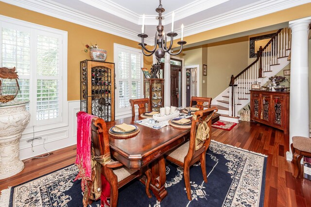 dining area with wood finished floors, stairway, a wainscoted wall, a chandelier, and ornamental molding