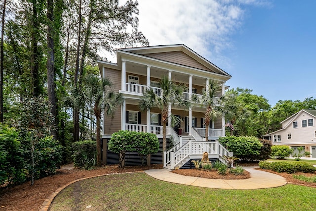 view of front of property with a porch, a balcony, stairs, and a front yard