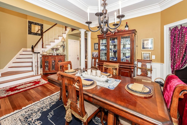 dining room with ornamental molding, wood finished floors, stairway, a wainscoted wall, and a notable chandelier