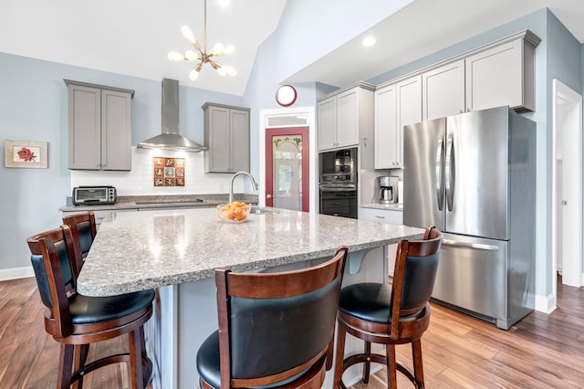 1064 Blackbear Dr, Edisto Island, SC 29438 - kitchen with black appliances, wall chimney range hood, wood finished floors, gray cabinetry, and vaulted ceiling