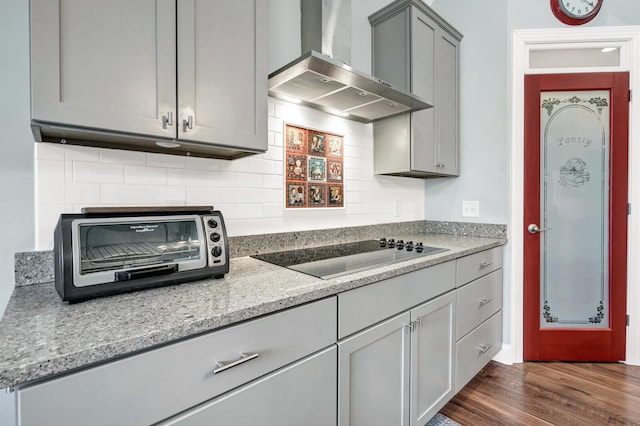 1064 Blackbear Dr, Edisto Island, SC 29438 - kitchen featuring wall chimney range hood, black electric cooktop, gray cabinetry, tasteful backsplash, and dark wood-type flooring