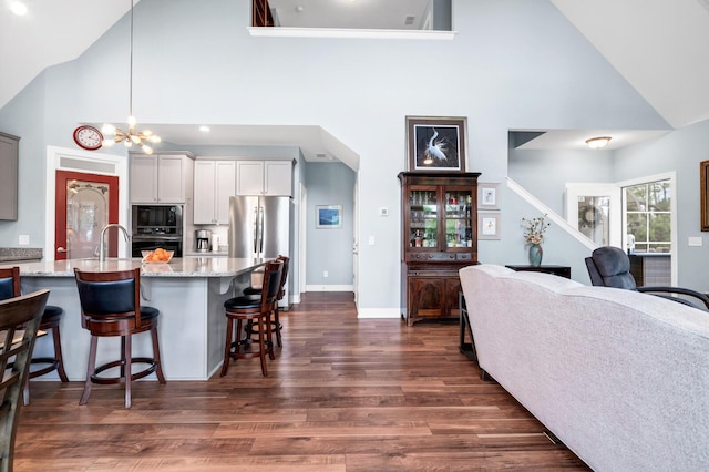1064 Blackbear Dr, Edisto Island, SC 29438 - kitchen featuring black appliances, high vaulted ceiling, dark wood finished floors, a breakfast bar, and light stone countertops