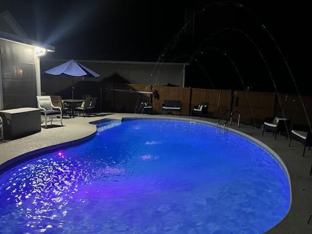 pool at twilight with a patio area