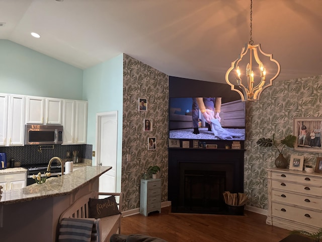 kitchen featuring dark wood-type flooring, white cabinetry, vaulted ceiling, pendant lighting, and light stone countertops