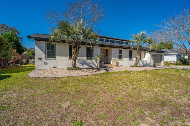 rear view of property featuring stucco siding, a lawn, a garage, fence, and crawl space