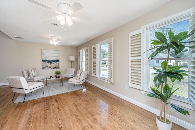 sitting room featuring visible vents, ceiling fan, baseboards, and wood finished floors